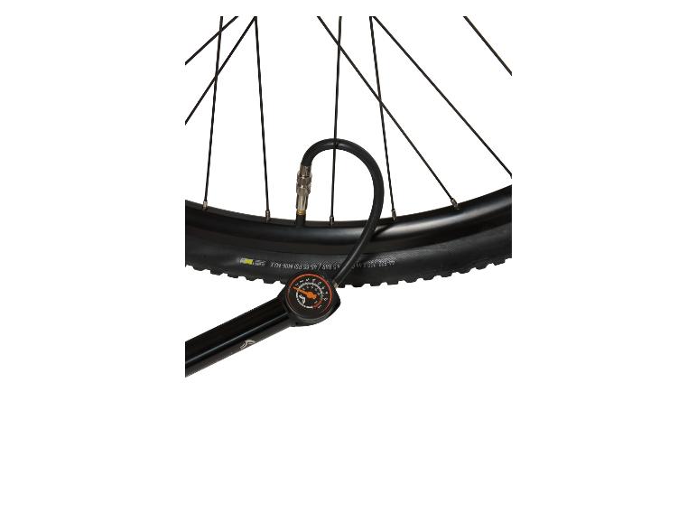 Pumpička na kolo s manometrem připojená k černé pneumatice kola.