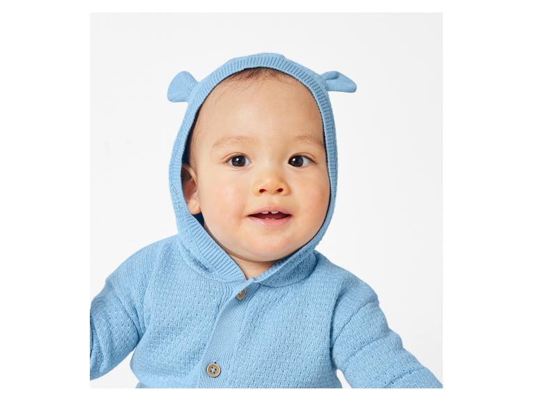 Dítě v modrém pleteném svetru s kapucí.