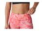 Žena v růžových legínách se vzorem a černé sportovní podprsence, vkládá klíč do kapsy.