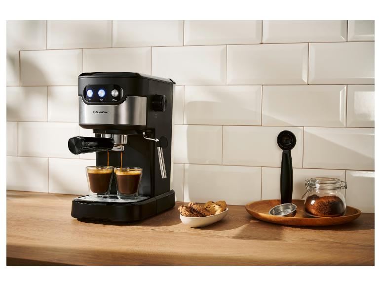 Černý a stříbrný kávovar na espresso připravuje dva šálky kávy v moderní kuchyni.