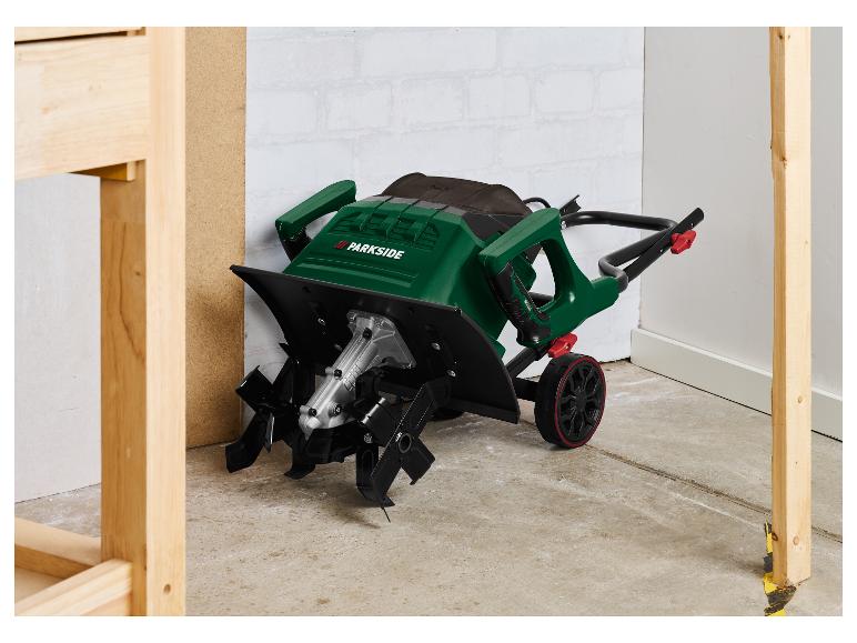 Zelený elektrický kultivátor Parkside s koly na betonové podlaze.