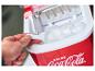 Ruka bere kostky ledu z červeného výrobníku ledu Coca-Cola.
