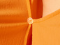 Detail oranžového trička s knoflíkem.