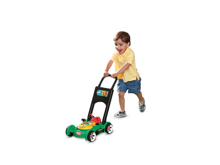 Šťastný chlapec si hraje se zelenou hračkou sekačky na trávu Little Tikes.