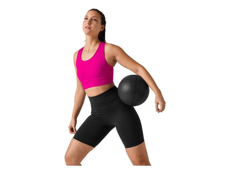 Žena ve sportovním oblečení drží medicinbal.