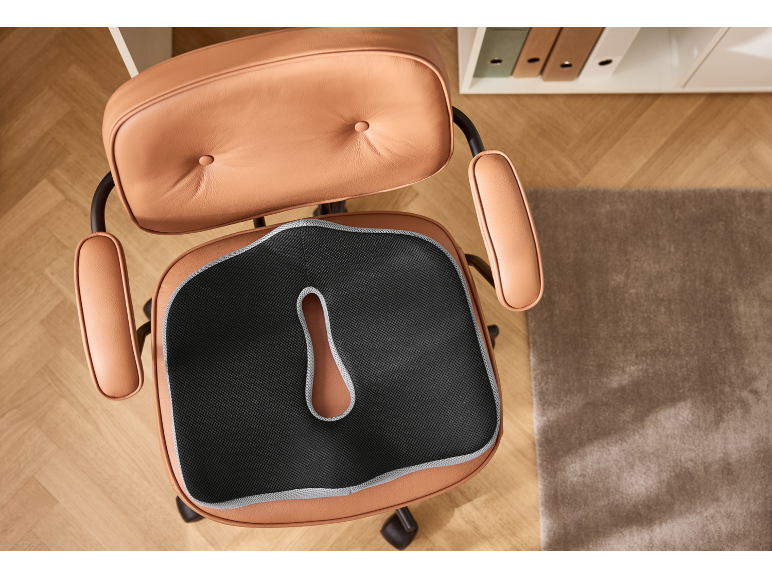 Ergonomický polštář na hnědé kožené kancelářské židli, pohled shora.