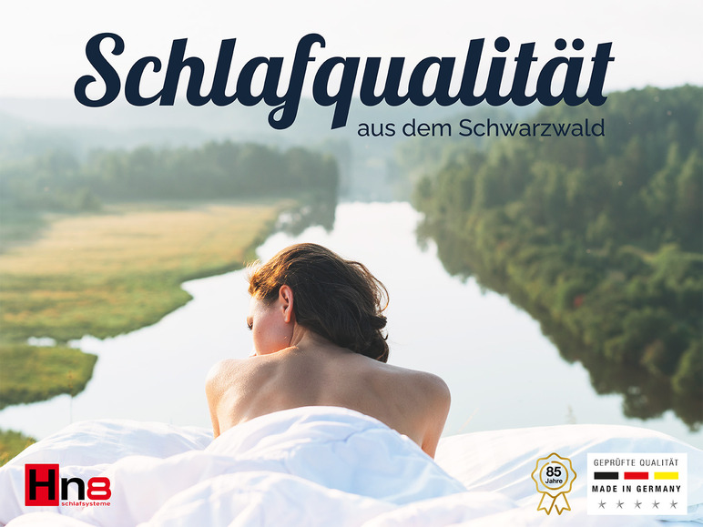 Žena leží na ložním prádle s řekou a lesy v pozadí, reklama na spánkové systémy Hn8.