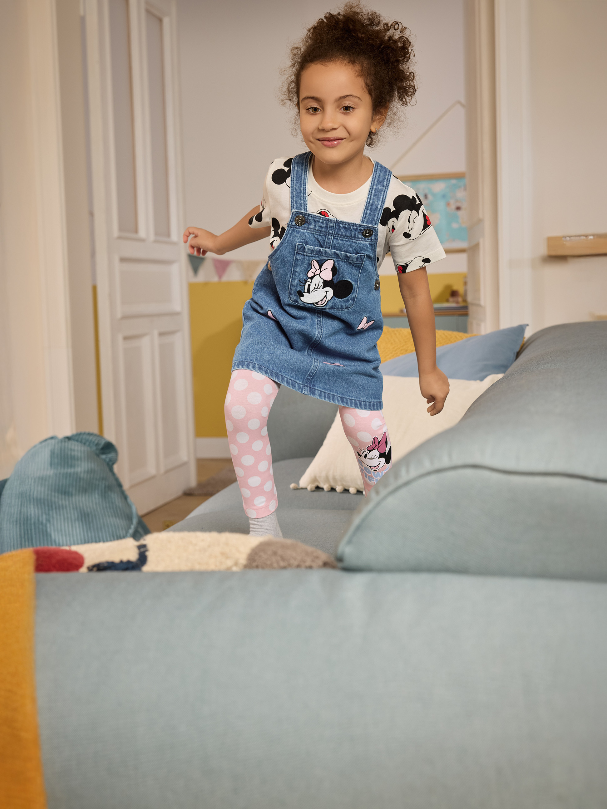 Dívka v džínových šatech s Minnie Mouse a růžovými puntíkovanými legínami