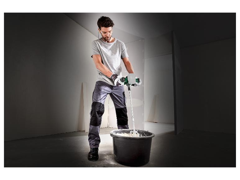 Muž míchá stavební materiál elektrickým míchadlem.