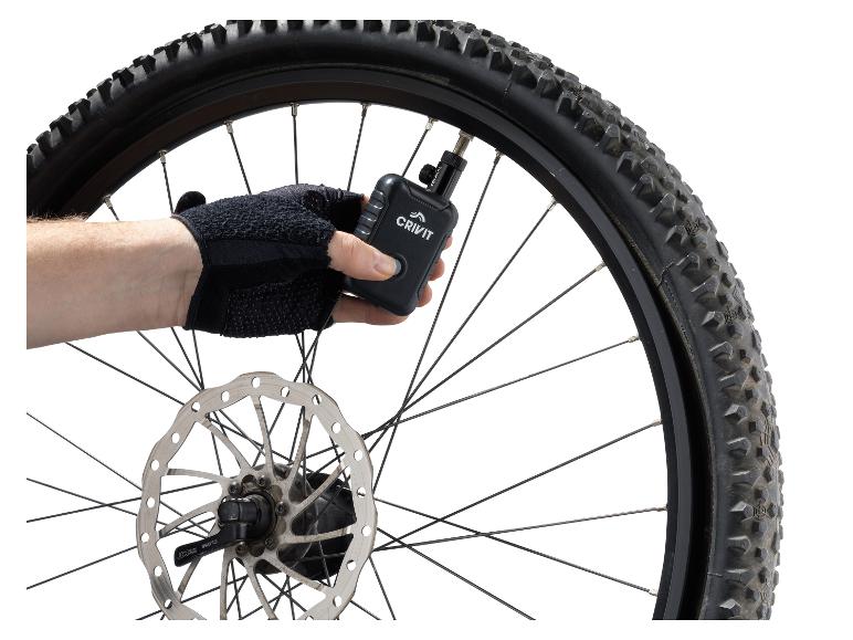 Ruka v rukavici nafukuje pneumatiku kola Crivit digitální vzduchovou pumpou.