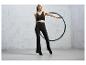 Žena v černém sportovním oblečení s modrou hula hoop.