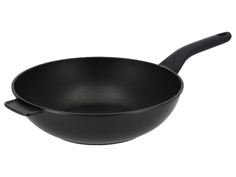 Černá wok pánev s dlouhou rukojetí a menší rukojetí na opačné straně.