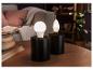 Dvě černé lampy s kulatými a kapkovitými LED žárovkami na dřevěném stole.