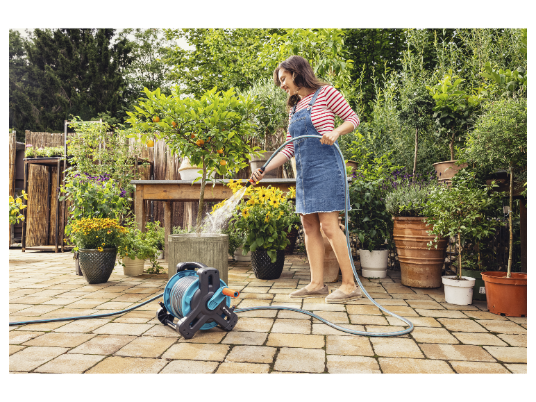 Žena zalévá květiny v květináčích zahradní hadicí Gardena.