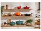 Stylová kuchyně s litinovými hrnci Le Creuset v zelené, oranžové a červené barvě.