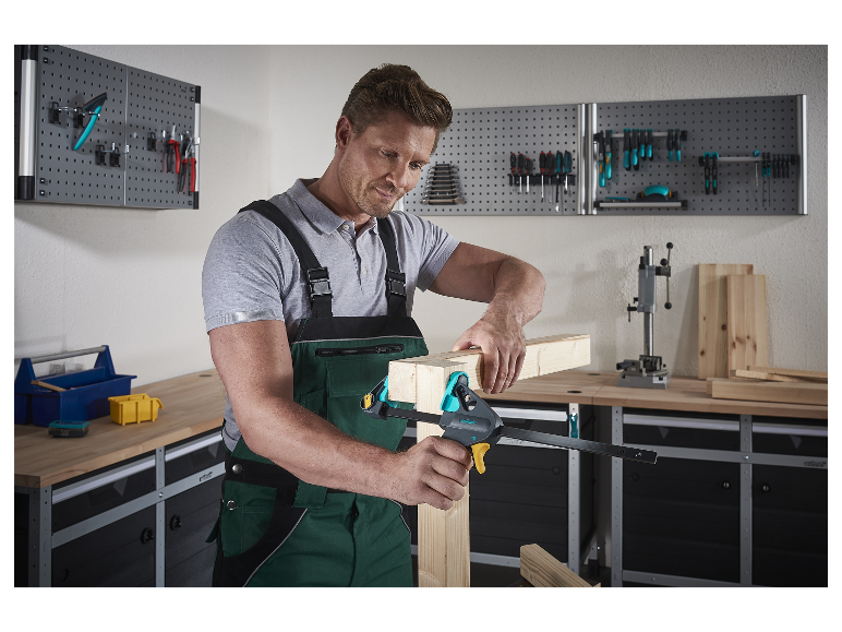 Muž v dílně používá svěrku Wolfcraft k spojení dřevěných dílů.