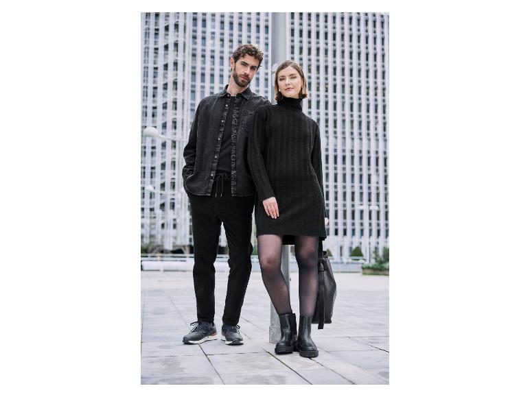 Pár v elegantním černém oblečení před moderními budovami.