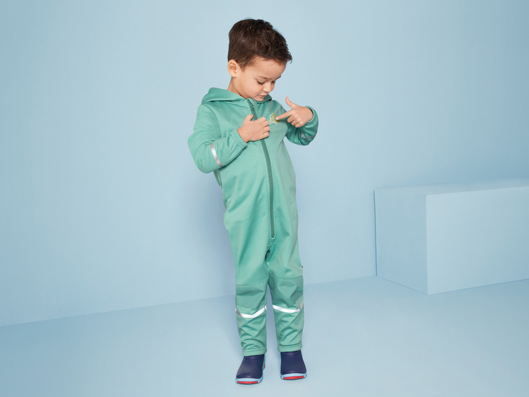 Dítě v zeleném overal s reflexními detaily.