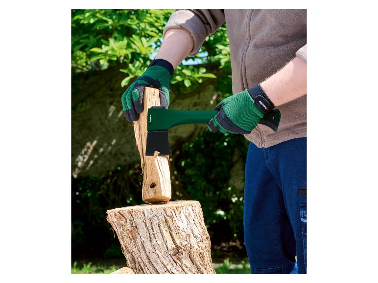 Osoba v zelených rukavicích štípe dřevo sekerou Parkside.