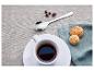 Espresso káva v bílém šálku s sušenkami a kávovými zrny na lněném ubrusu.