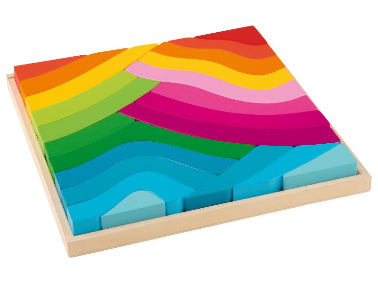 Dřevěná puzzle s bloky v duhových barvách v dřevěném rámu.