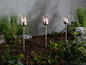 Tři stříbrné zahradní lampy s LED plameny v zahradě