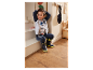 Malý chlapec sedí na schodech v oblečení a botách Paw Patrol.