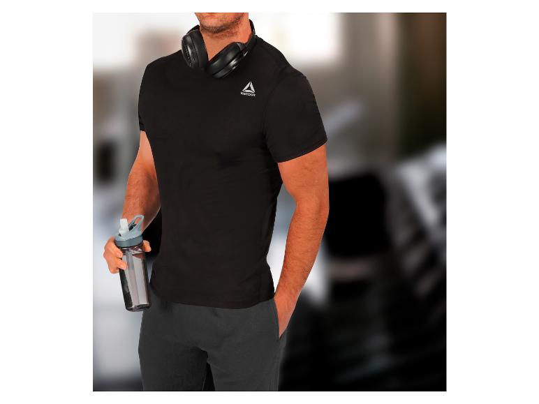 Muž v černém tričku Reebok s lahví vody a sluchátky.