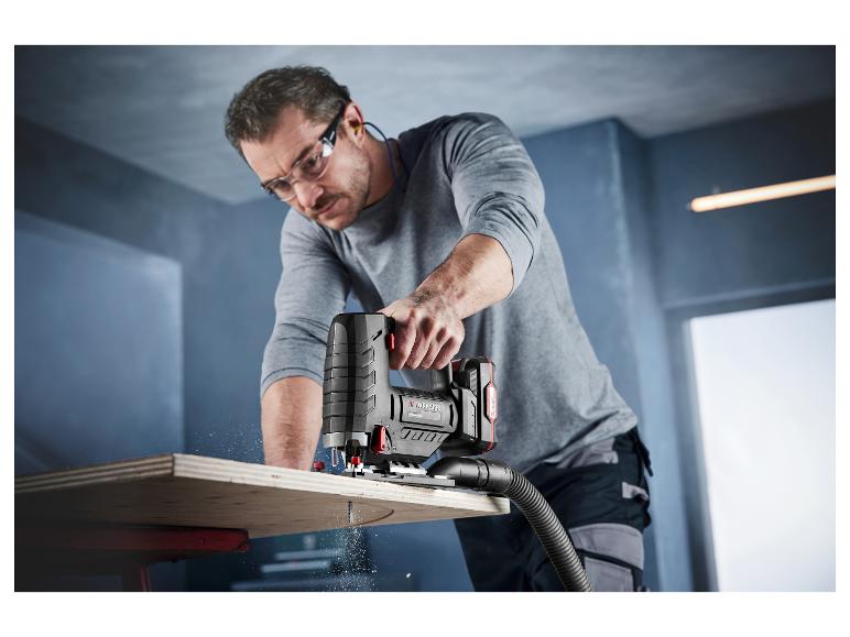 Muž používá akumulatovou přímočarou pilu Parkside na řezání překližky.
