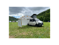 Volkswagen Transporter s markýzou a stanem na kempu.
