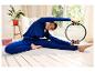 Žena v modrém sportovním oblečení používá kruh na pilates během protahovacího cvičení.