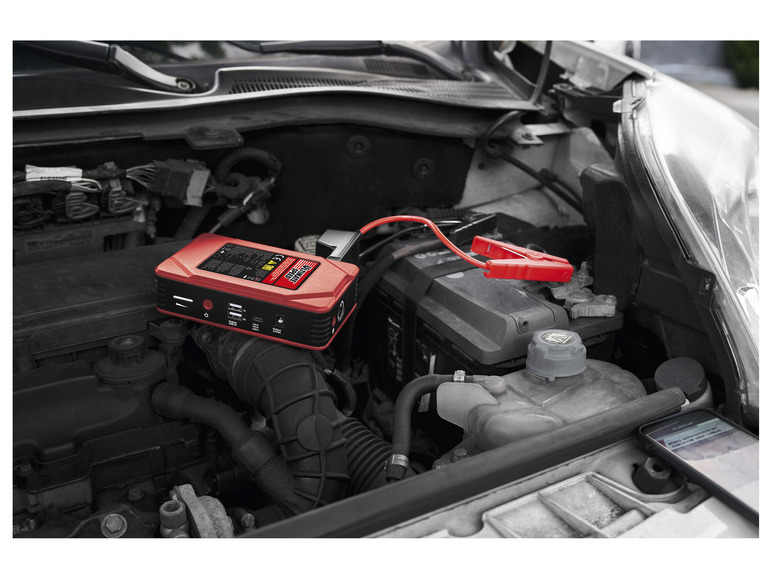 Červený autostarter Ultimate Speed ​​s kleštěmi v motorovém prostoru auta.