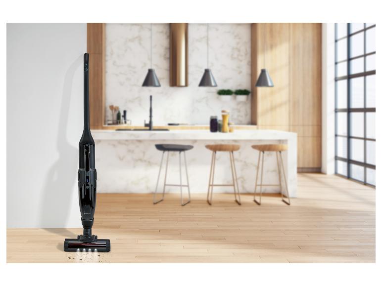 Černý bezdrátový vysavač s LED světly na dřevěné podlaze v moderní kuchyni