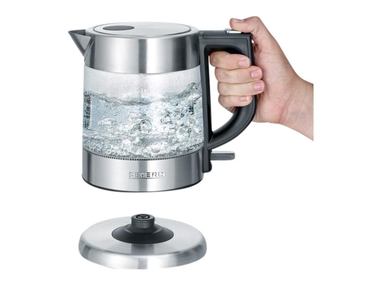 Skleněná rychlovarná konvice Severin s vařící vodou, držená rukou, vedle základny.