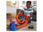 Usmívající se chlapec si hraje se sadou dráhy Hot Wheels Monster Trucks a autem.