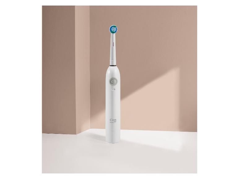 Bílý elektrický zubní kartáček Cien Beauty se zelenou a modrou hlavicí na béžovém pozadí