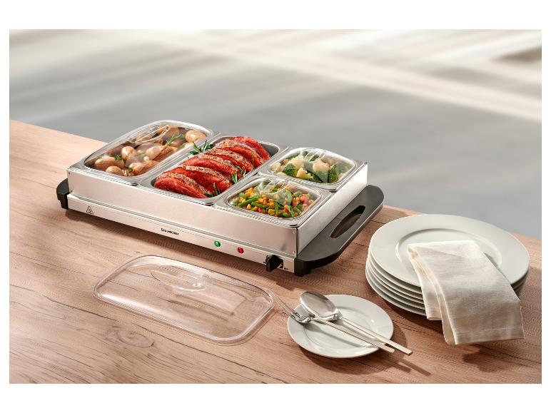 Nerezový ohřívač jídla s masem, bramborami a zeleninou na dřevěném stole.