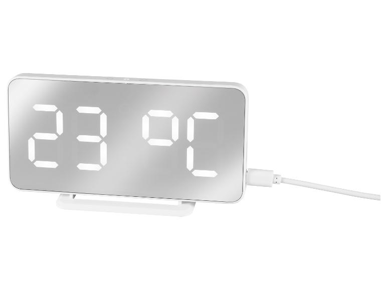 Bílý digitální budík s displejem teploty a nabíjecím kabelem
