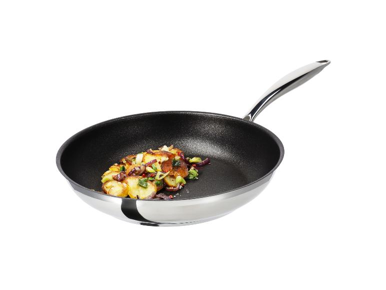 Smažené brambory s červenou cibulí a pórkem v černé pánvi se stříbrnou rukojetí
