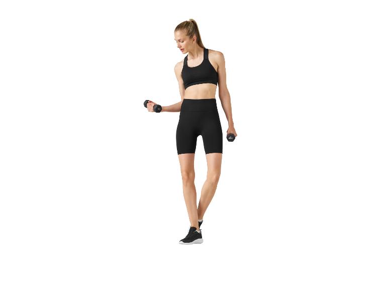 Žena v černé sportovní podprsence a šortkách, cvičící s 2 kg činkami.