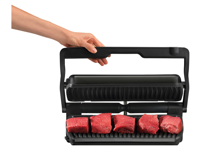 Černý gril s rukojetí, na kterém se griluje maso.