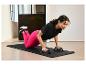 Žena dělá kliky na černé cvičební podložce s push-up úchopy.