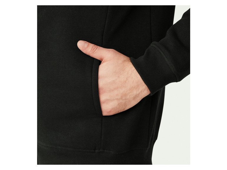 Detailní záběr černé mikiny s kapucí a kapsou.