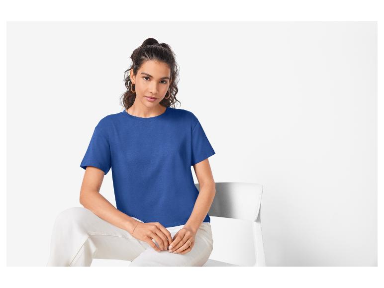 Modelka v modrém tričku a bílých kalhotách.