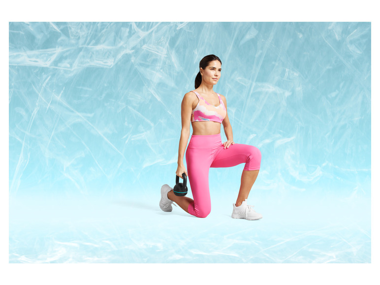 Žena v růžovém sportovním oblečení s kettlebellem