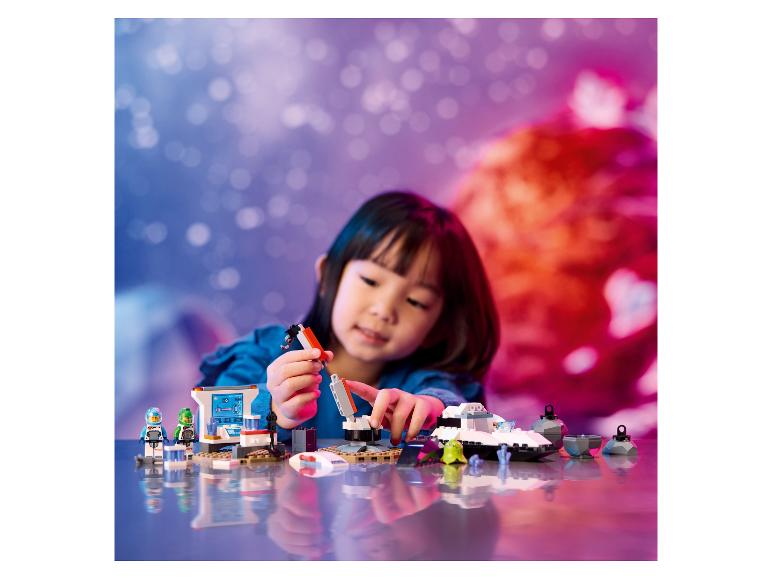 Dívka si hraje s LEGO City: Space, včetně vesmírné lodi a vesmírné základny.