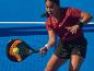 Žena hrající padel s pálkou a míčkem na modrém kurtu.