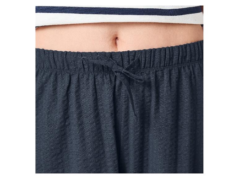 Břicho osoby v pruhovaném topu a tmavě modrých pyžamových kalhotách se šňůrkou.