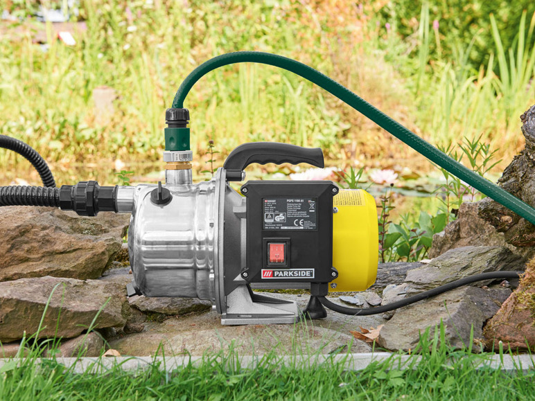 Stříbrná vodní pumpa Parkside s připojenou zelenou zahradní hadicí.