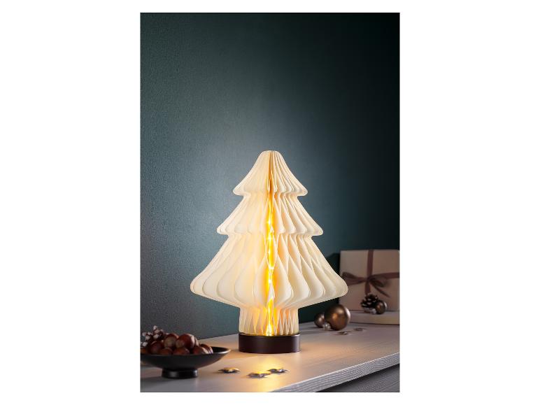 Dekorativní lampa ve tvaru vánočního stromku s teplými světly na stole.